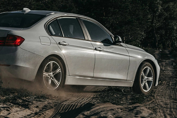 White BMW 3-Series driving on dirt