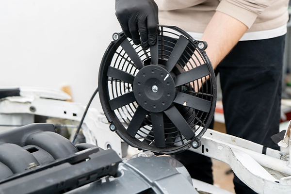 Technician holding cooling fan above engine bay